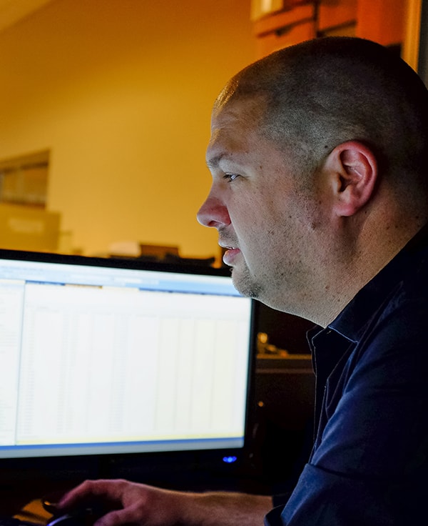 Profile of employee sitting at a desk looking at a computer screen