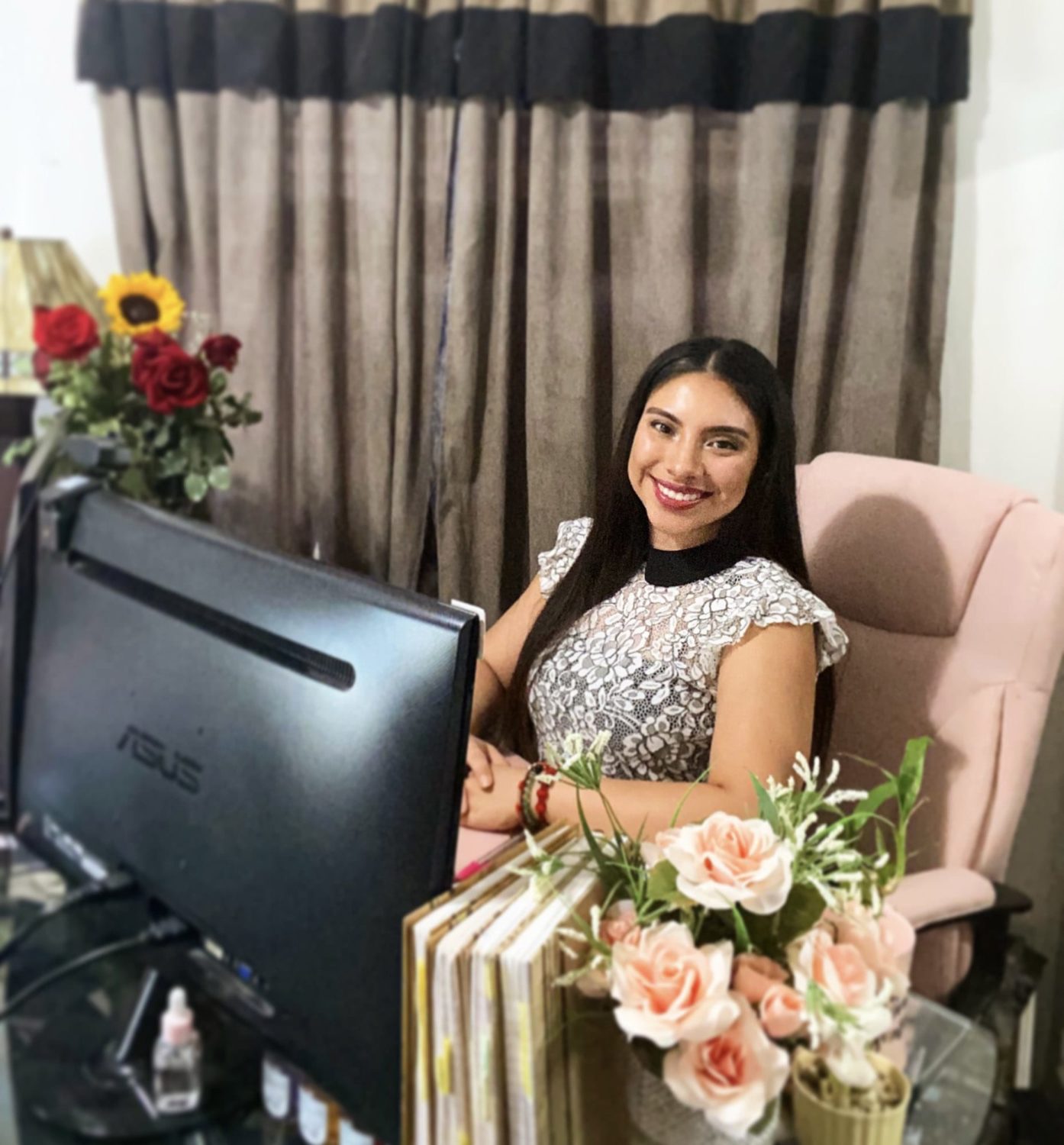 Woman sitting in a chair at a desk with a computer, smiling