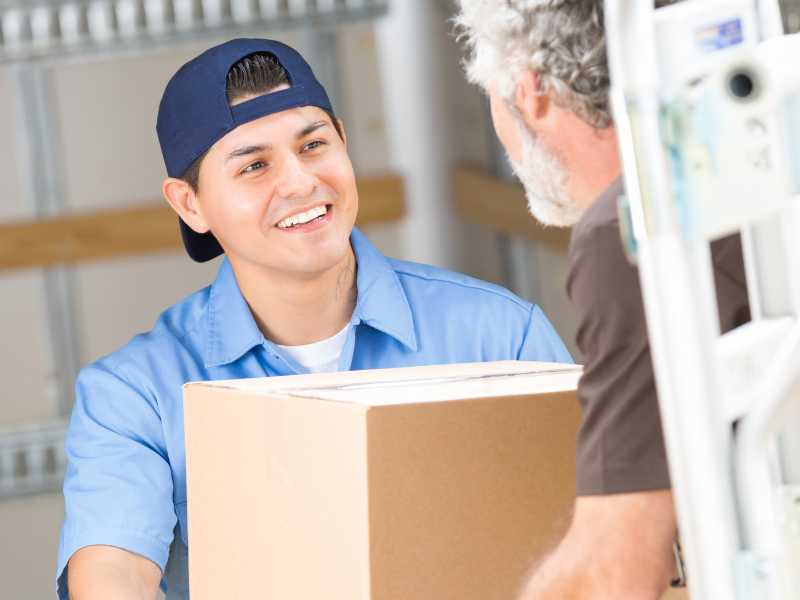 An AMS worker handing a box to a customer. 