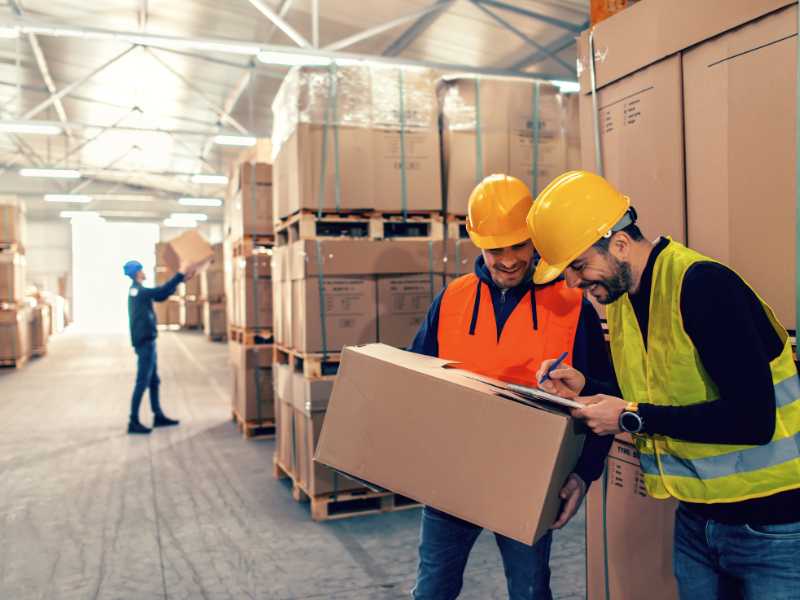 AMS Workers holding a package, writing on a clipboard.
