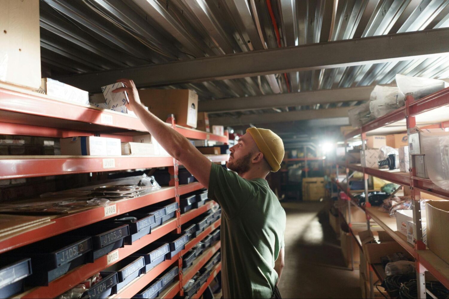 A person is pulling an item off a shelf in a warehouse.
