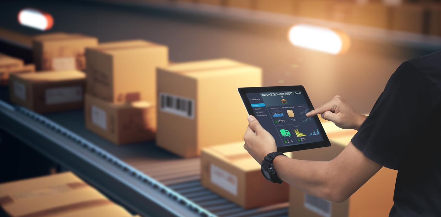 person on a tablet by a package conveyer belt - AMS Fulfillment