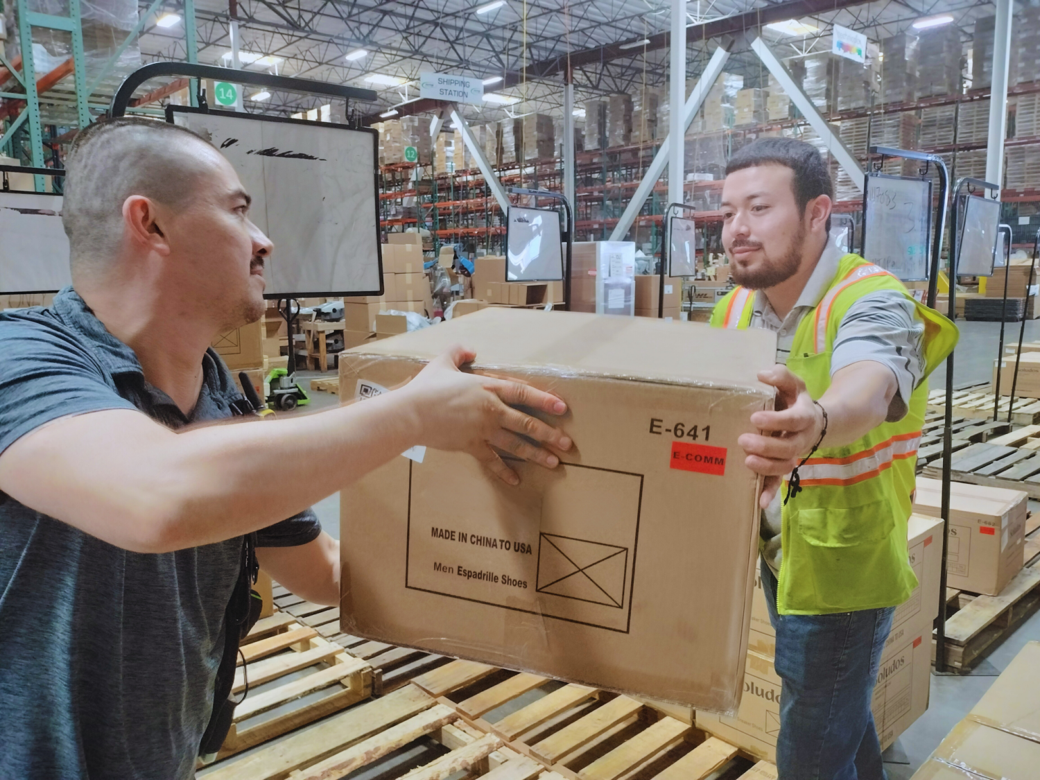 two men passing package to one another - AMS Fulfillment