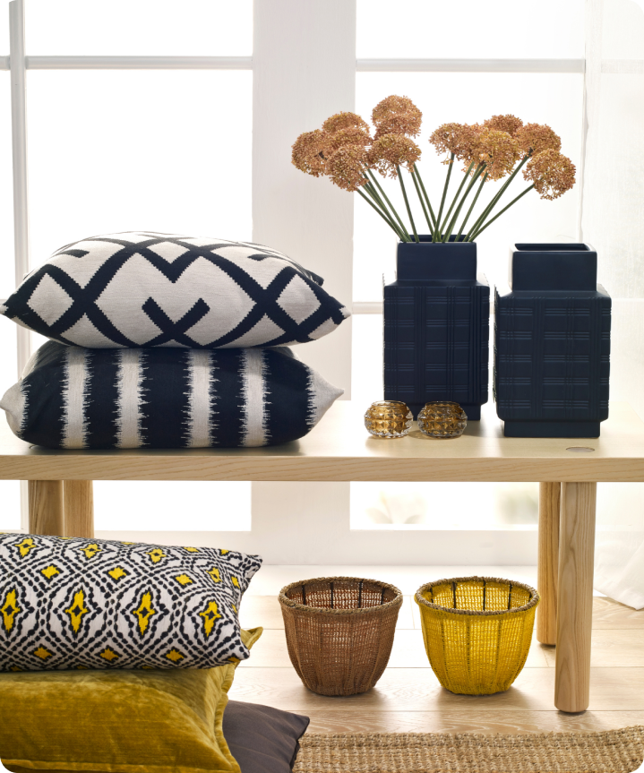 A small bench containing vases and pillows, with baskets and more pillows below it.