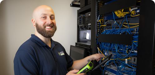 An AMS Fulfillment employee smiling at the camera while fixing some wires in a box.