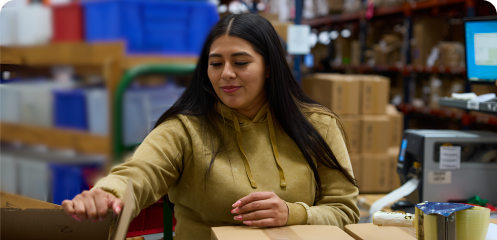 Person reaching for a new box, in a fulfillment warehouse.