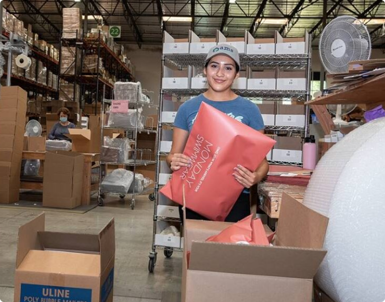 Person holding a Monday Swimwear package in an AMS warehouse.