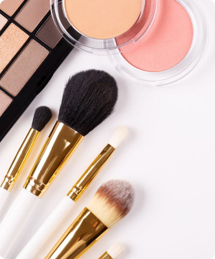Various makeup brushes, eye shadow and blush on a white surface.