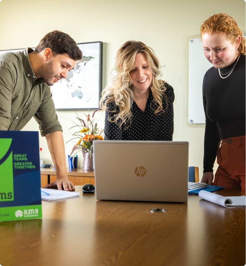 AMS employees standing and working on a laptop