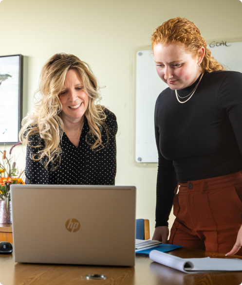 Two people standing, looking at a laptop screen.