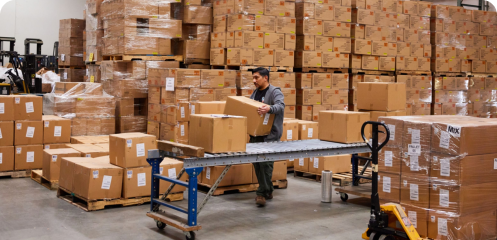 AMS Fulfillment employee stacking boxes from a conveyor belt.