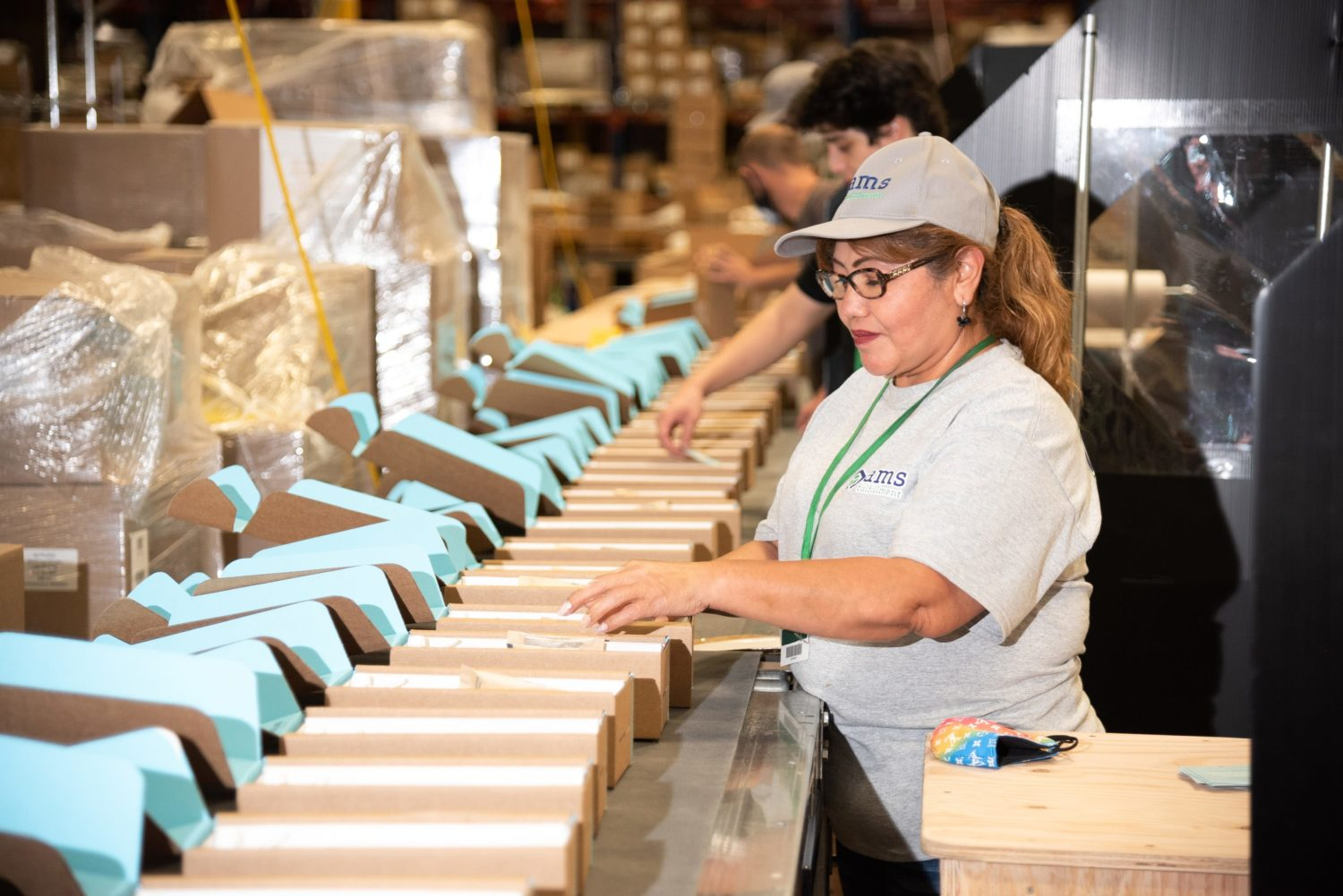 Image of assembly line workers putting boxes together to be shipped. 