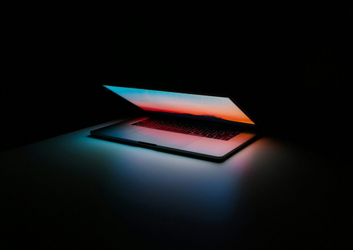 macbook partially open surrounded by darkness - AMS Fulfillment