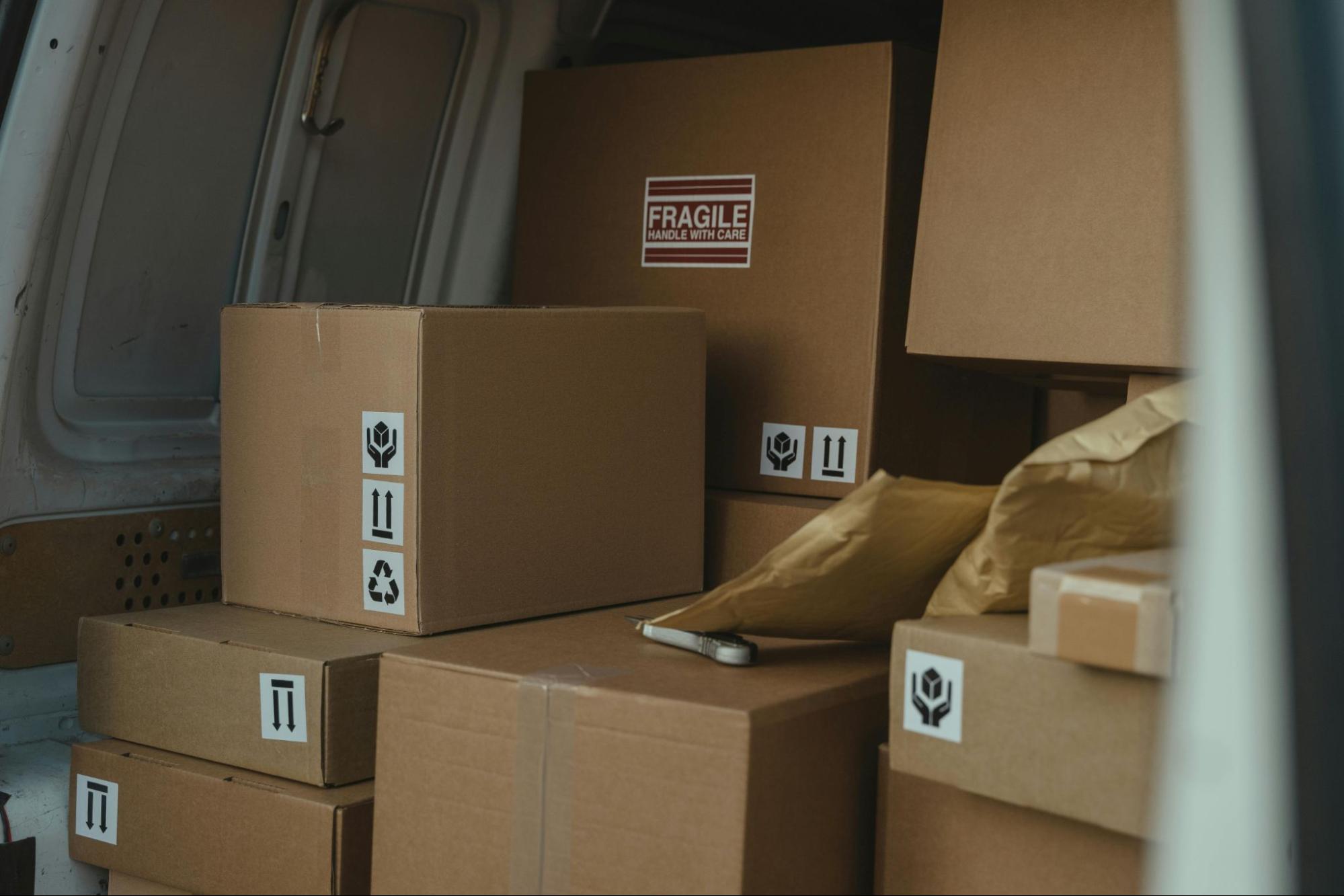 Packages are stacked on top of each other in the back of a van.