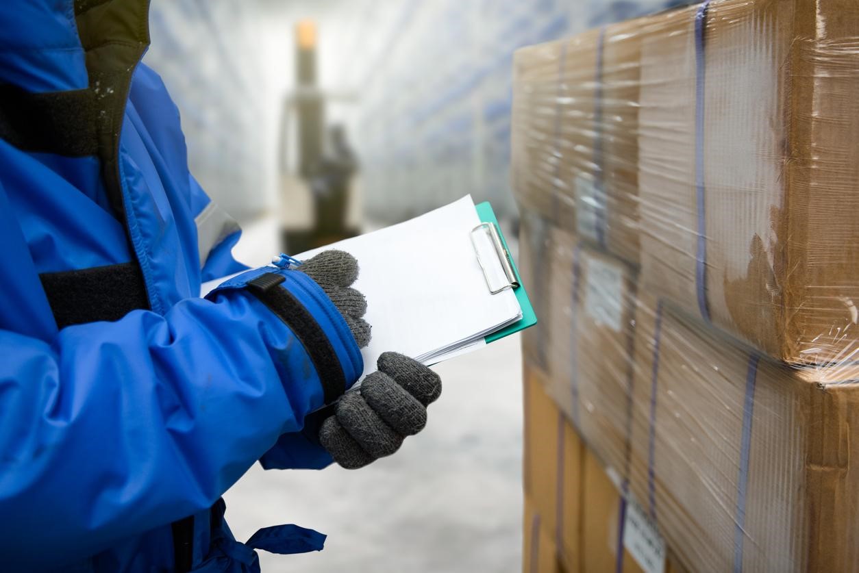 person in blue parka writing on clipboard by cold chain shipments - AMS Fulfillment