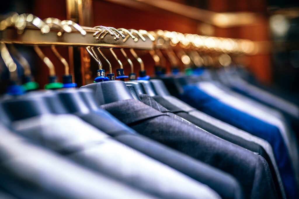 A close-up image of a clothing rack holding suits in several different colors.