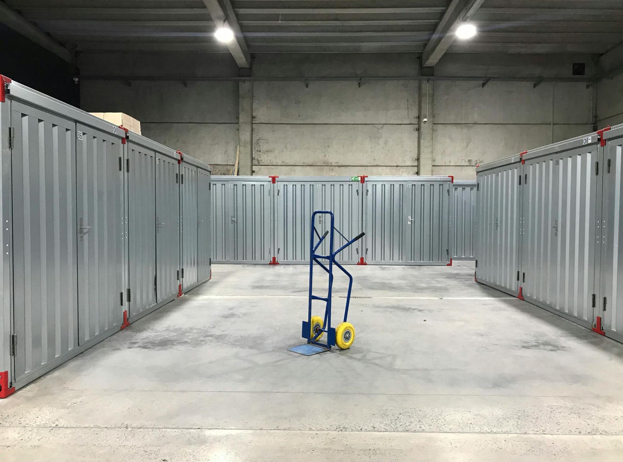 A blue dolly with yellow wheels is sitting in the middle of a cold storage facility.