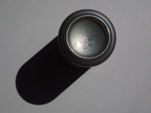 An image of the bottom of a soda can, with the can casting a shadow to the right.