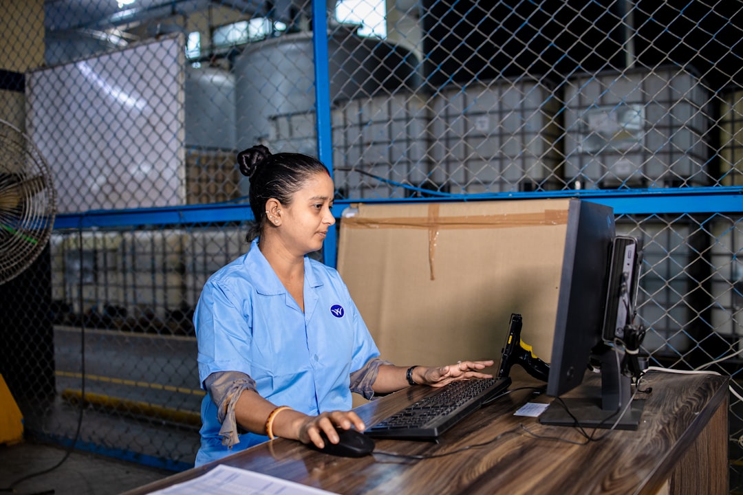 A person is looking at something on a desktop computer, in a warehouse setting.