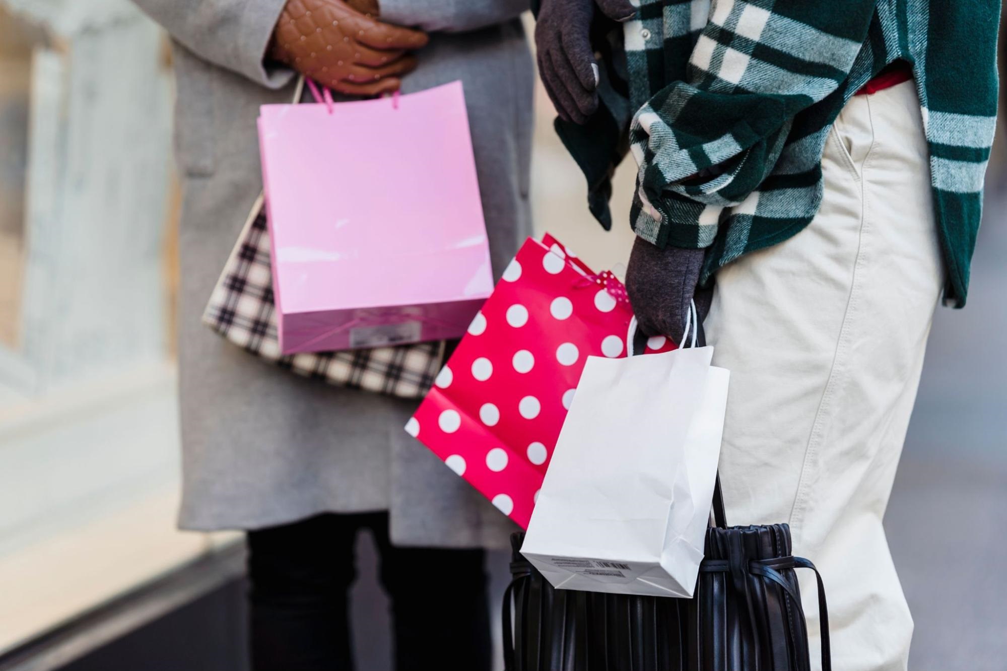 Two people are carrying multiple shopping bags.